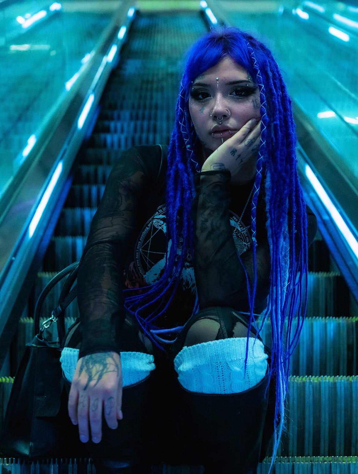 Retrato de Nea Aurora con trenzas azules en una escalera mecánica