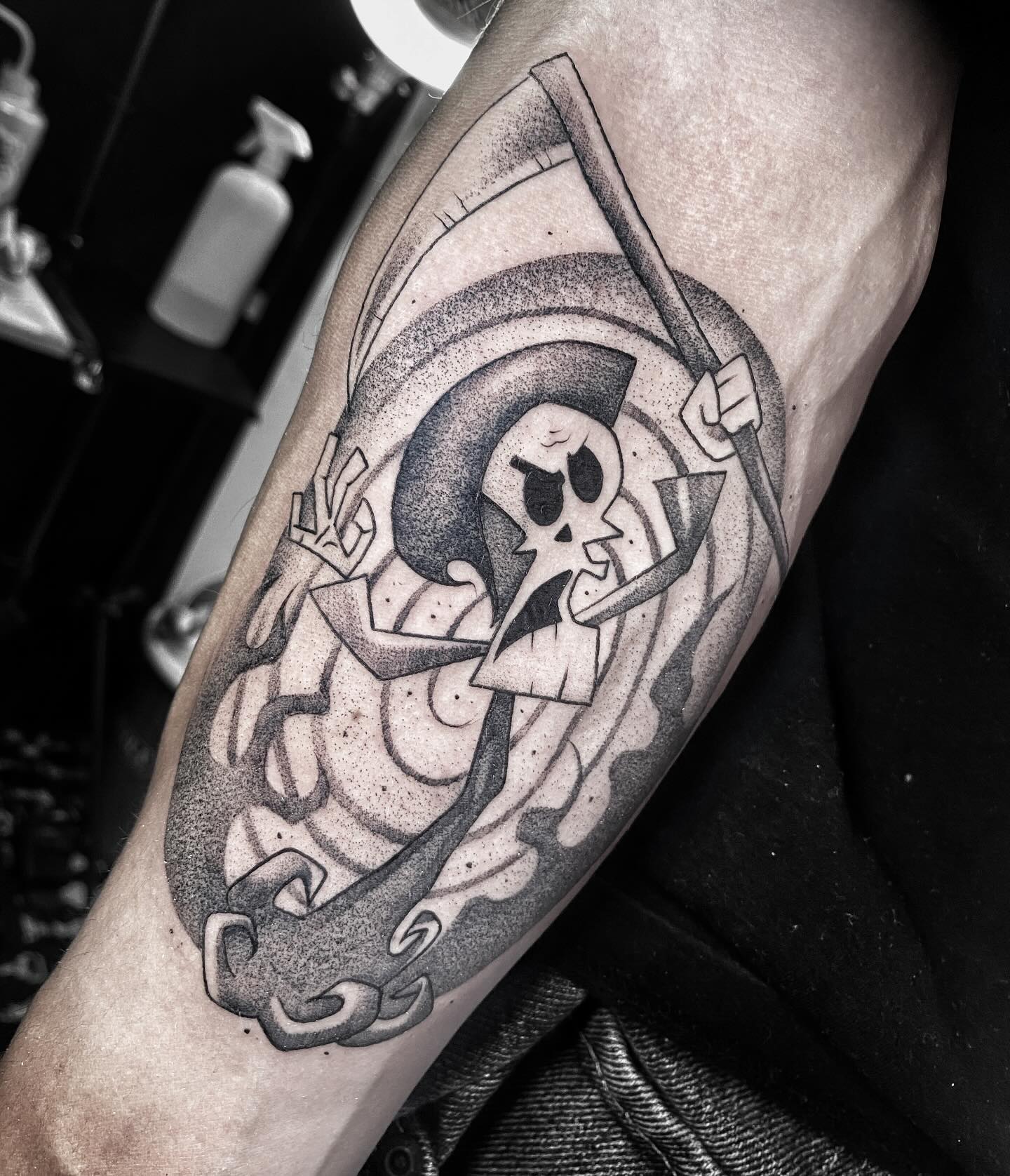 Tatuaje ilustrativo del Segador con guadaña, sombreado en puntillismo sobre el brazo