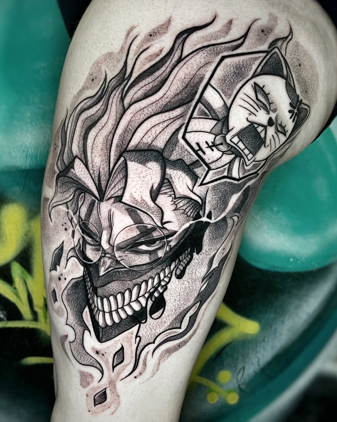 Tatuaje blackwork de villano anime enmascarado entre llamas y una figura felina en la pantorrilla
